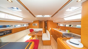 A yacht interior with a dining area, seating, a kitchen, and a galley. - Sun-Kissed Sailing Adventure in the Stunning Islas Cícladas (Paros)