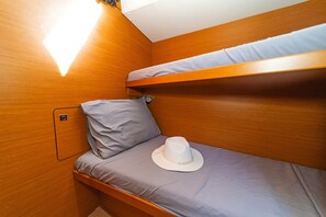 A compact cabin with two bunk beds, a pillow, and a hat on the lower bunk. - Sun-Kissed Sailing Adventure in the Stunning Islas Cícladas (Paros)