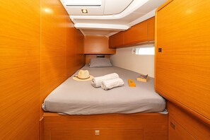 A narrow, wooden-paneled cabin with a single bed, a small window, and a storage compartment. - Sun-Kissed Sailing Adventure in the Stunning Islas Cícladas (Paros)