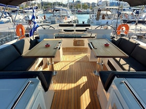A boat deck with seating, tables, and life rings. - Sun-Kissed Sailing Adventure in Islas Sarónicas (Alimos)