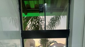 A glass door leading to a pool area with a patio, outdoor furniture, and a view of a house in the background. - LUXURIOUS HOUSE IN MARINAS DI CALDAS CONDOMINIUM (caldas novas)