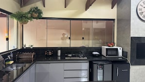 A modern kitchen with a black countertop, stainless steel appliances, and a hanging plant. - LUXURIOUS HOUSE IN MARINAS DI CALDAS CONDOMINIUM (caldas novas)