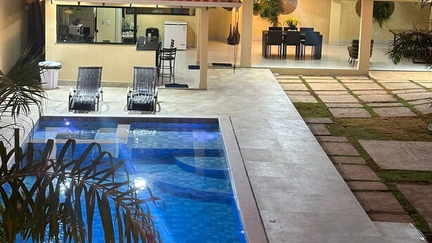 A residential property with a swimming pool, outdoor seating, and a tiled roof. - LUXURIOUS HOUSE IN MARINAS DI CALDAS CONDOMINIUM (caldas novas)