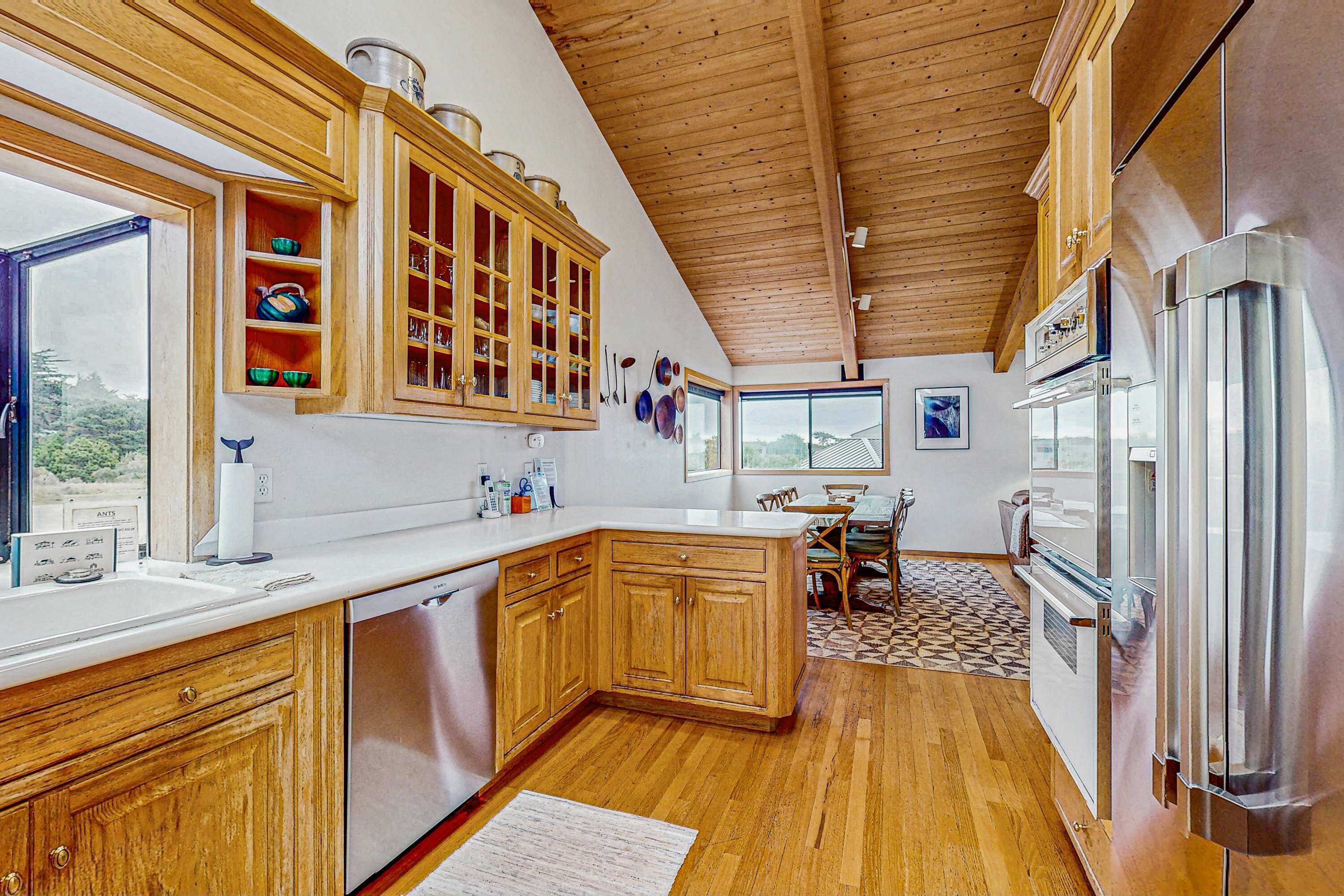 A kitchen with wooden cabinets, a stainless steel refrigerator, and a window providing a view of the outdoors.