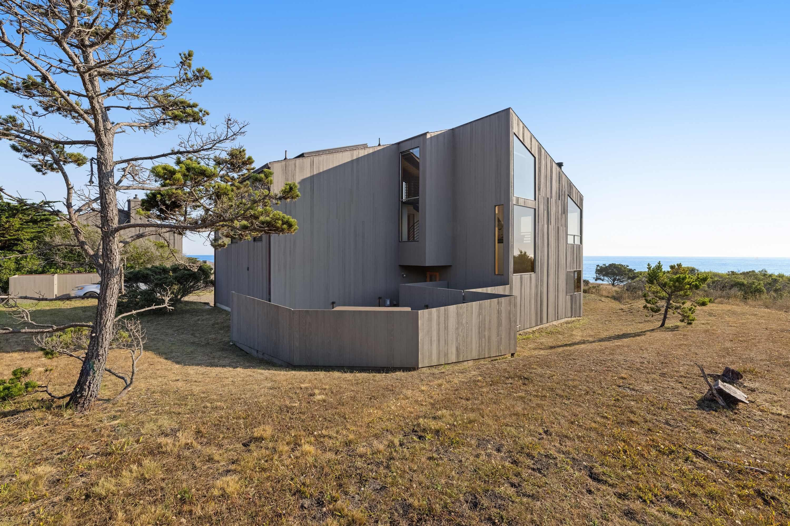 A modern house with a large window, a balcony, and a view of the sea.