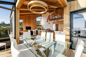 Een moderne keuken met houten details, een eetgedeelte met glazen tafels, en uitzicht op de omgeving.