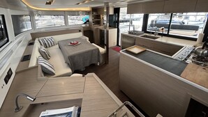 En kompakt autocamper indretning med spiseplads, tekøkken og siddeområde med hynder.