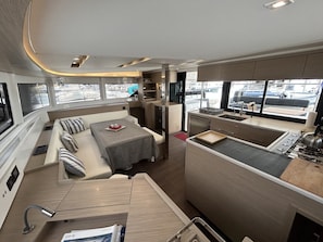A compact RV interior with a dining area, kitchenette, and a seating area with cushions.