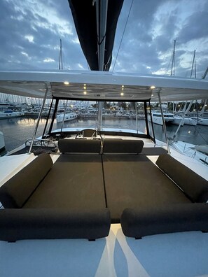 A boat deck with a covered seating area, a steering wheel, and a view of a marina with multiple boats. - Sun-Kissed Sailing Adventure in Islas Esporadas (Skiathos)