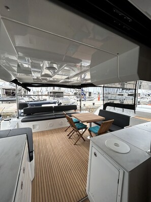 A boat's interior with a dining area, seating, and a view of the marina. - Sun-Kissed Sailing Adventure in Islas Esporadas (Skiathos)