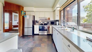 A modern kitchen with a large window, stainless steel appliances, and a view of the outdoors. - Sea Ranch 4BR oceanfront home with private hot tub near Shell Beach (Sea Ranch)
