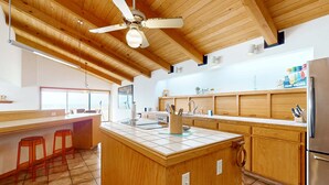 Eine moderne Küche mit Holzausstattung, einer zentralen Kochinsel und einem Deckenventilator.