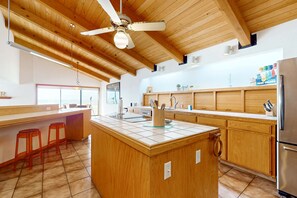 Eine moderne Küche mit Holzausstattung, einer zentralen Kochinsel und einem Deckenventilator.