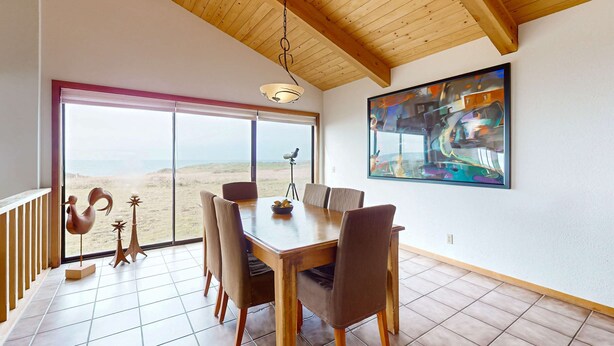 Ein Essbereich mit einem Holztisch, Stühlen, einem großen Fenster mit Blick und einem Bild an der Wand.