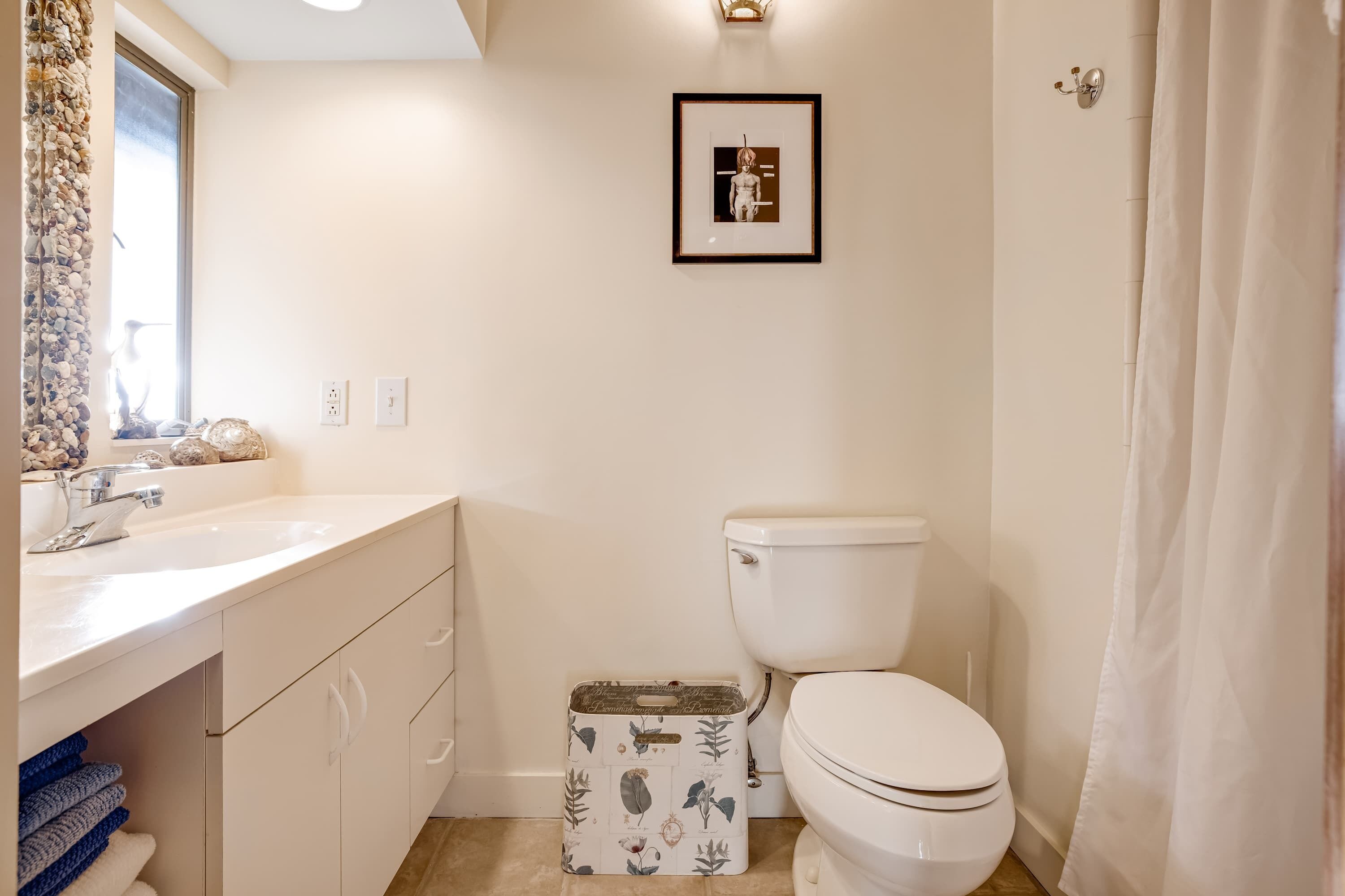 Une salle de bain avec des toilettes, un lavabo et une œuvre d’art encadrée au mur.