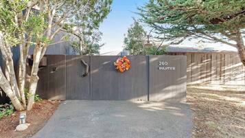 A gated entrance with a wooden fence, a number sign '260 Solstice,' and a flower arrangement.