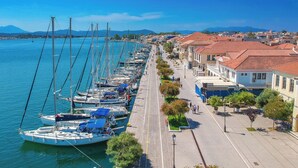A marina with boats docked along a waterfront promenade, lined with buildings and trees. - Sun-kissed Sailing Adventure in the Ionian Islands (Preveza)