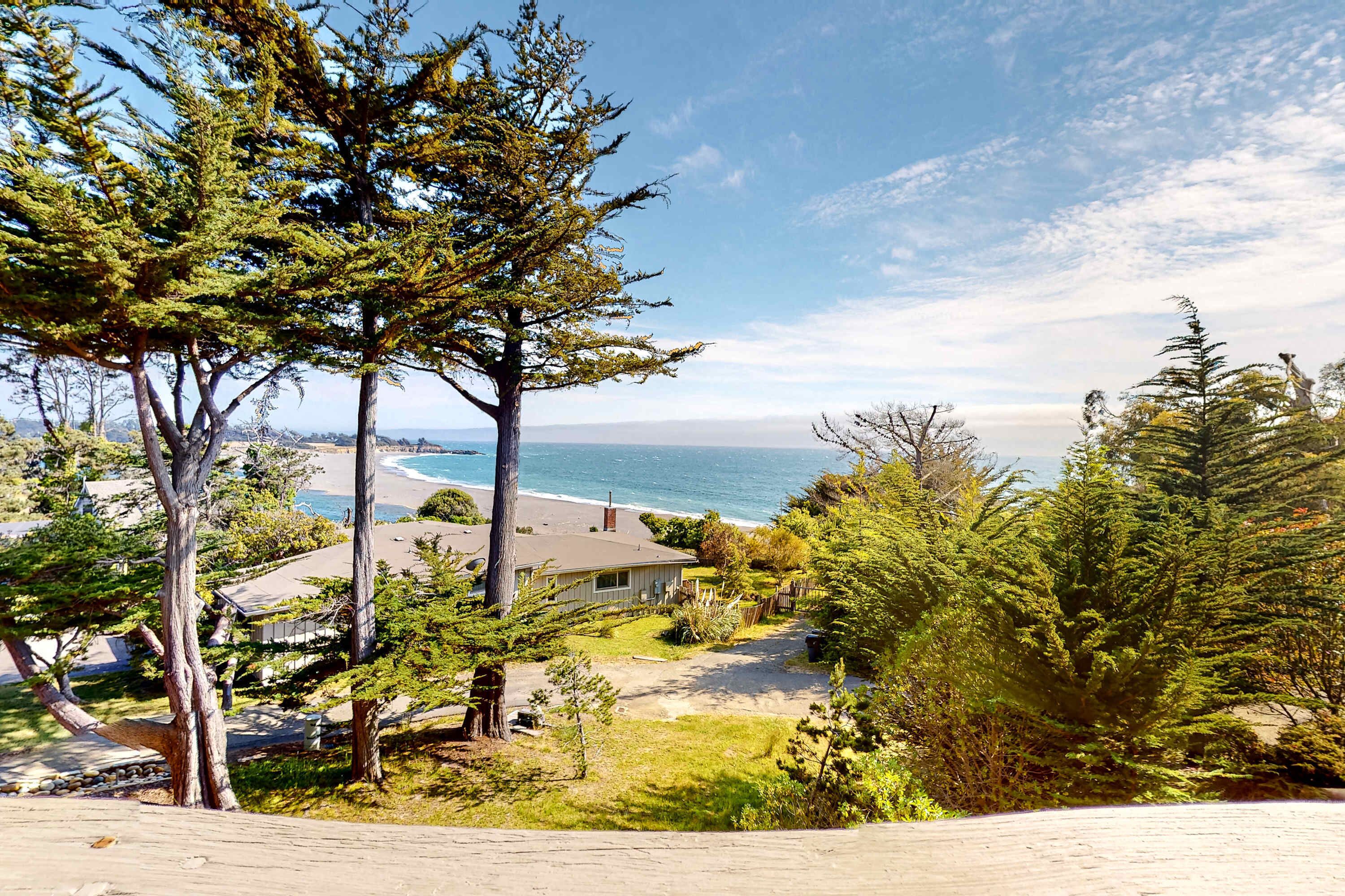 A coastal residential area with houses, trees, and a beach view.