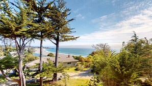 A coastal residential area with houses, trees, and a beach view. - Updated home with ocean views, private hot tub, fire table, outdoor kitchen (Gualala)