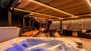 A hot tub with a wooden deck and outdoor furniture, a barbecue area, and a kitchen. - Updated home with ocean views, private hot tub, fire table, outdoor kitchen (Gualala)
