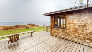 En träveranda med en stol och ett bord, med utsikt över havet.