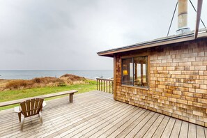 Eine Holzterrasse mit Stuhl und Tisch, mit Blick auf den Ozean.