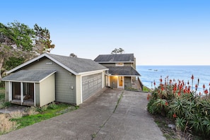 Ein zweistöckiges Haus mit Garage und überdachter Veranda, mit Blick auf das Meer.
