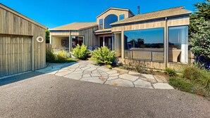 A modern house with a stone pathway, large windows, and a wooden fence. - Sea Ranch 2BR modern ocean-view home on golf course with hot tub (Sea Ranch)