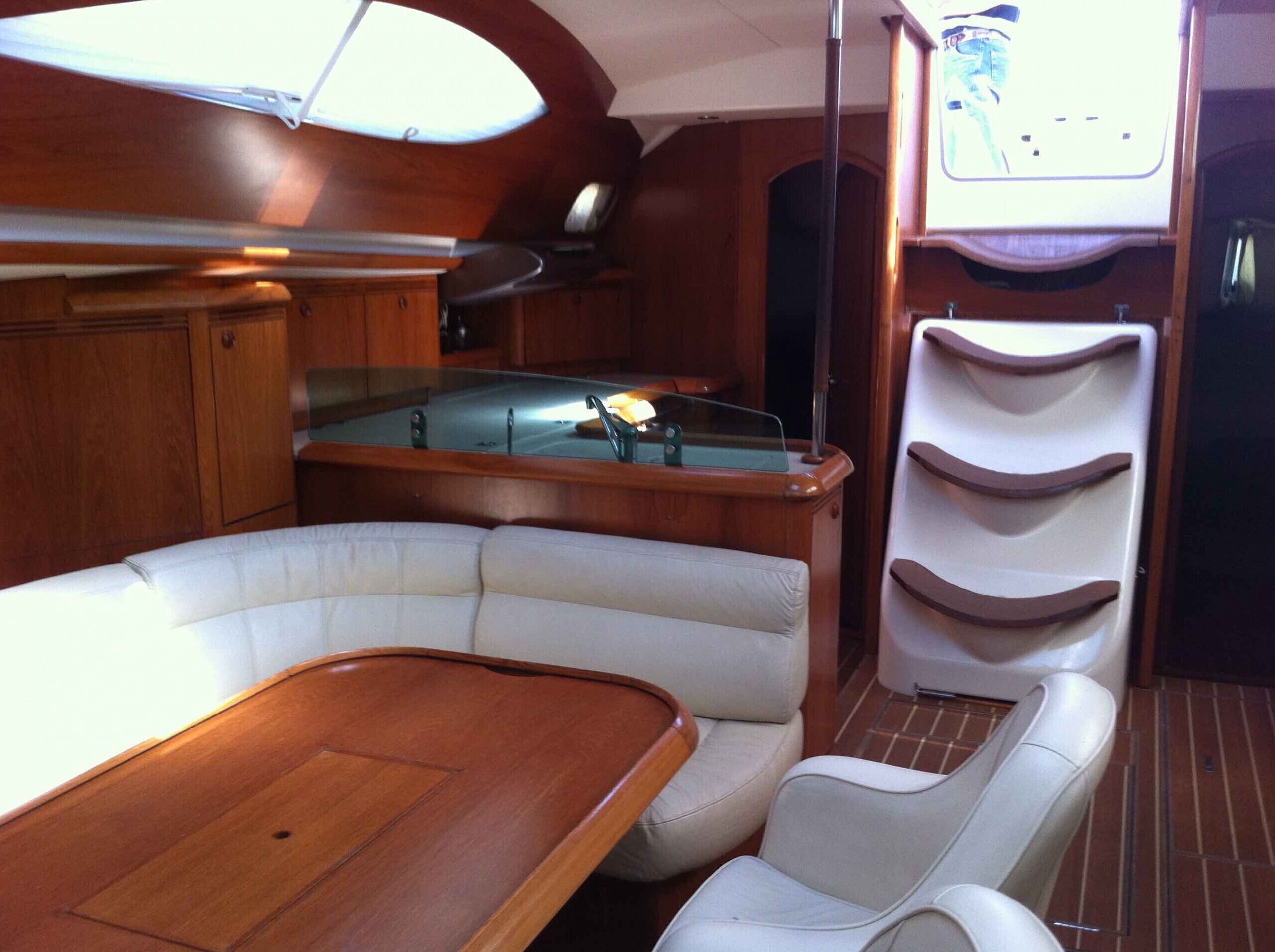 A boat interior with a wooden table, cushioned seating, a pool table, and a television.