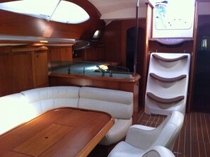 L’intérieur d’un bateau, avec une table en bois, des sièges rembourrés, une table de billard et un téléviseur.