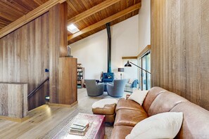 A wooden interior with a leather sofa, a fireplace, and a staircase. - Sea Ranch 3BR meadow home with private hot tub near Black Point Beach (Sea Ranch)