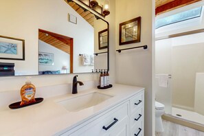 Un baño moderno con un espejo grande, un lavabo blanco y zona de ducha.
