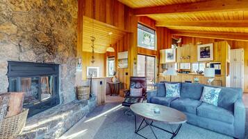 A cozy interior with a stone fireplace, a sofa, a coffee table, and wooden walls.
