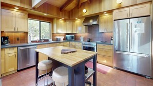 Una cocina moderna con armarios de madera, electrodomésticos de acero inoxidable y una isla central con taburetes.