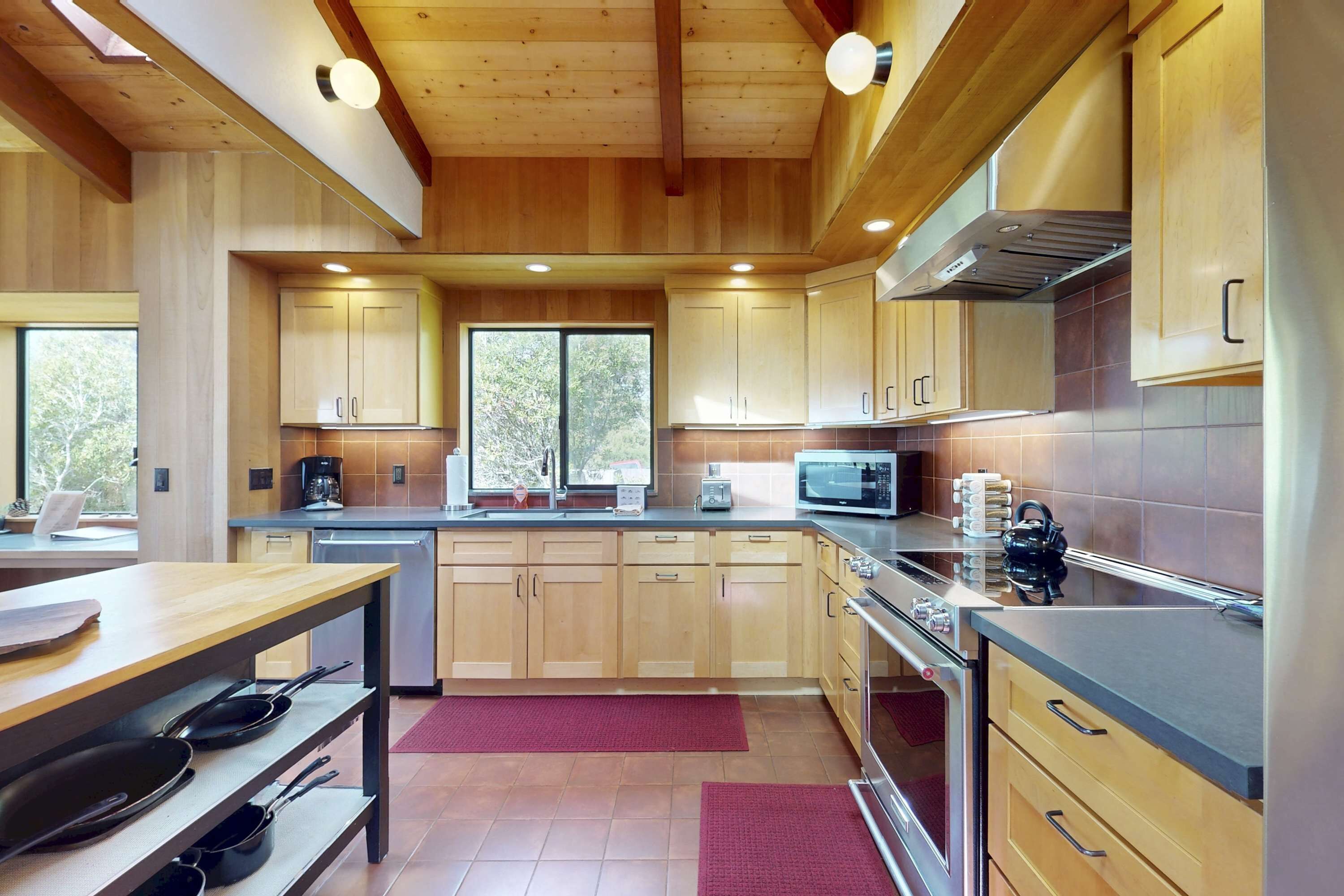 A modern kitchen with wooden cabinets, a stainless steel stove, and a microwave.