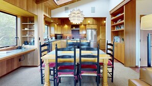 Una cocina moderna con armarios de madera, una isla central y un comedor con mesa y sillas.