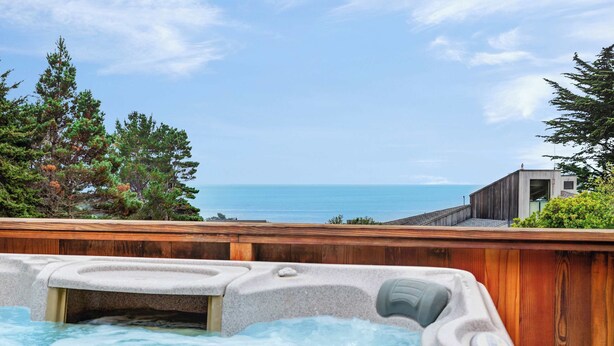 Un jacuzzi con terraza de madera y vista al océano.