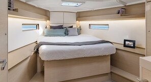 Ein kompakter, gut beleuchteter Schlafzimmer mit Bett, Nachttischen und einem Dachfenster.
