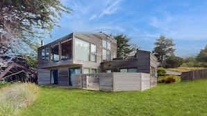 Een modern huis met twee verdiepingen, grote ramen, een plat dak en een verzorgd gazon.