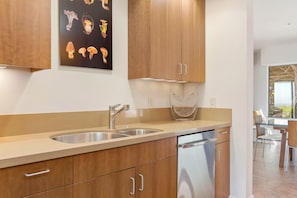A modern kitchen with wooden cabinets, a stainless steel sink, and a dishwasher. - Oceanfront home with fireplace, EV charger & ocean views (Sea Ranch)