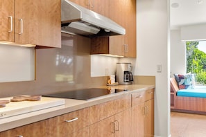 A modern kitchen with stainless steel appliances, wooden cabinets, and a built-in oven. - Oceanfront home with fireplace, EV charger & ocean views (Sea Ranch)