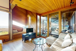Ein modernes Wohnzimmer mit einer Couch, einem Glastisch und einem Fernseher auf einer Holzkommode.