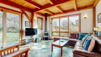 A cozy living room with a fireplace, leather sofa, and large windows.