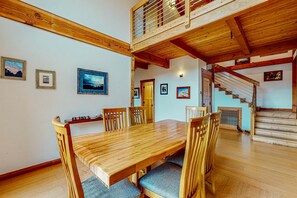 A wooden dining table with chairs, a staircase, and a loft area with a railing. - Sea Ranch 3BR home, two decks & partial ocean views — dog welcome (Sea Ranch)