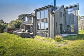 A modern wooden house with large windows, a deck, and outdoor seating. - Sea Ranch 3BR home, two decks & partial ocean views — dog welcome (Sea Ranch)