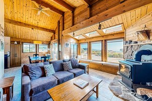 A wooden interior with a sofa, dining table, and a wood-burning stove. - Sea Ranch home with hot tub & ocean views, dogs welcome (Sea Ranch)