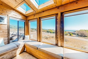 A wooden interior with large windows, a bench, and a skylight. - Sea Ranch home with hot tub & ocean views, dogs welcome (Sea Ranch)