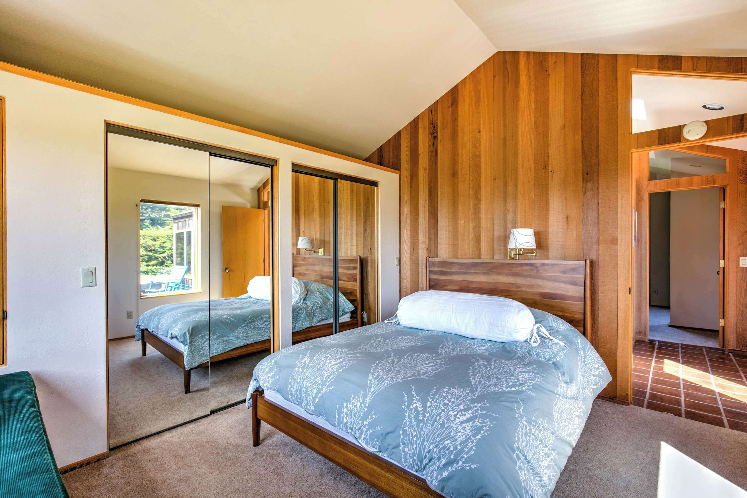 Ein Schlafzimmer mit zwei Betten, Holzwänden, einem Spiegel und Blick ins Freie.