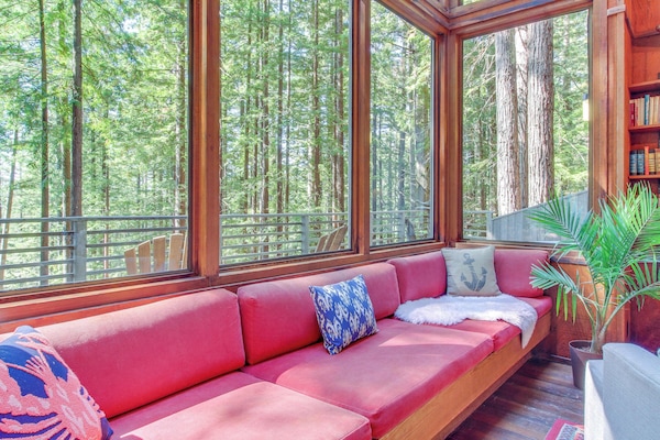Curl up on the plush red sofa, where you can lose yourself in a good book while enjoying the lush forest views.