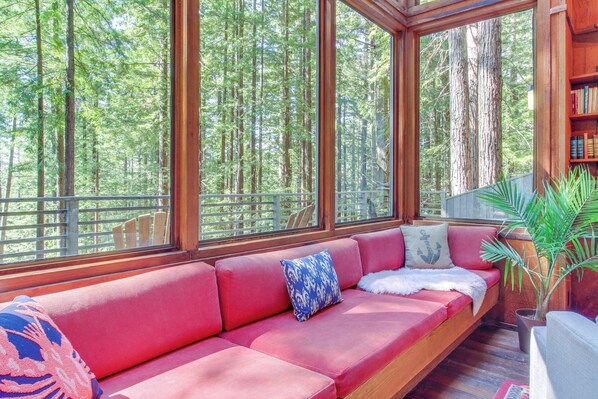 Une terrasse en bois avec un canapé rouge, une plante en pot et une bibliothèque.